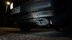 Hand platziert GPS Tracker hinter Autostoßstange – GPS Tracker versteckt einbauen